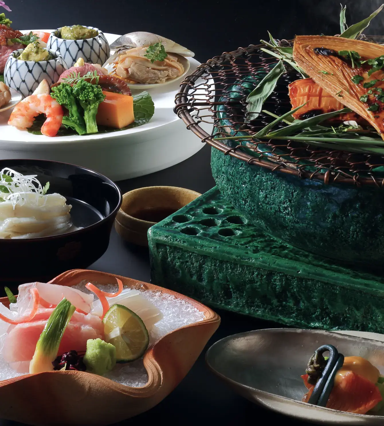   漆黒の背景に、エビや刺身、彩り豊かな野菜などが精巧に盛り付けられた日本料理が上から並べられています。