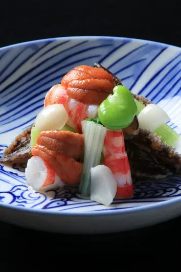 赤い盆の中央、ガラス器のエビと野菜に緑のモミジ葉が添えられた涼しげな一皿。