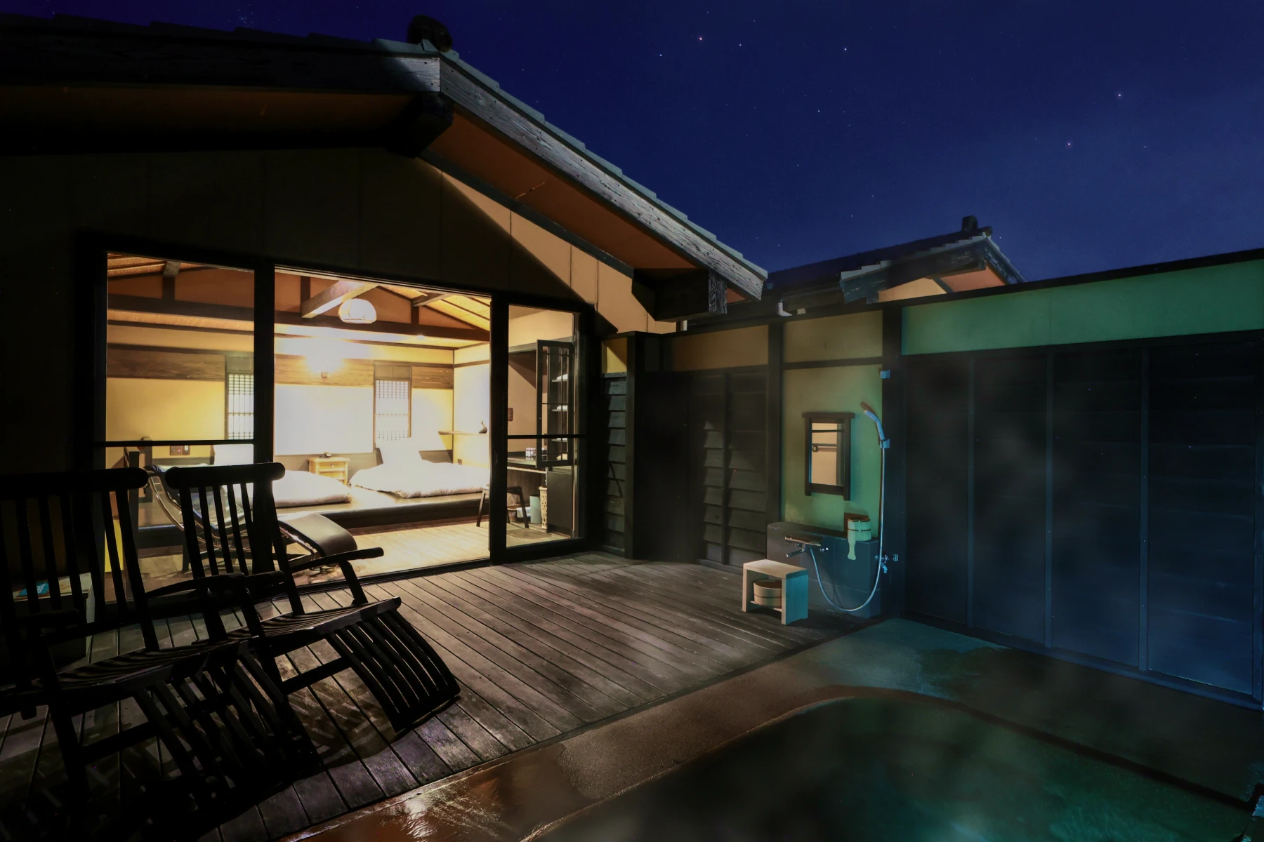 花タイプ客室：客室の夜景。広々としたウッドデッキには屋外風呂があり、その奥には大きな窓越しにツインベッドが配置された和洋室が見える。空には星が瞬いている。